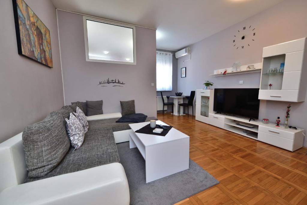 a living room with a white couch and a tv at Studio apartman Čvek in Osijek
