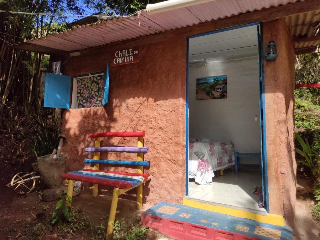 圣路易斯-杜帕赖廷加Pousada e Hostel Cantinho dos Chalés的外面有五颜六色的椅子的房子