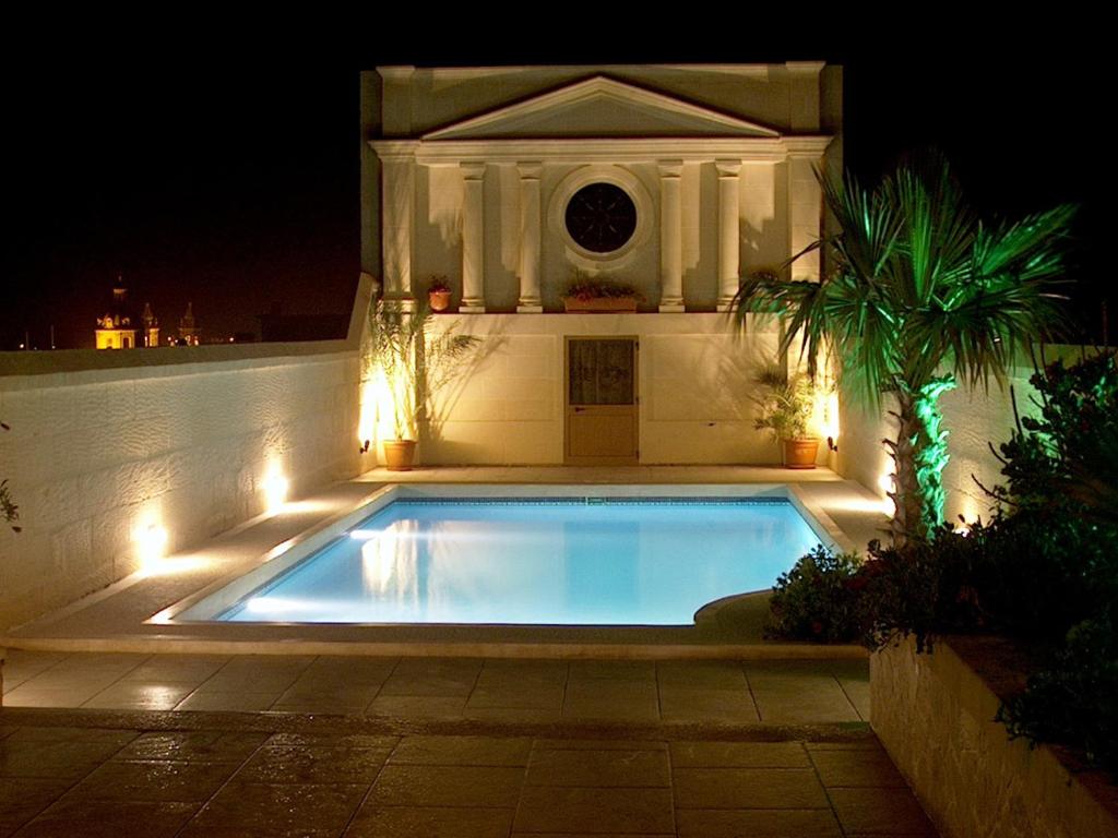 a swimming pool with lights in front of a house at Villa Palma in Sannat