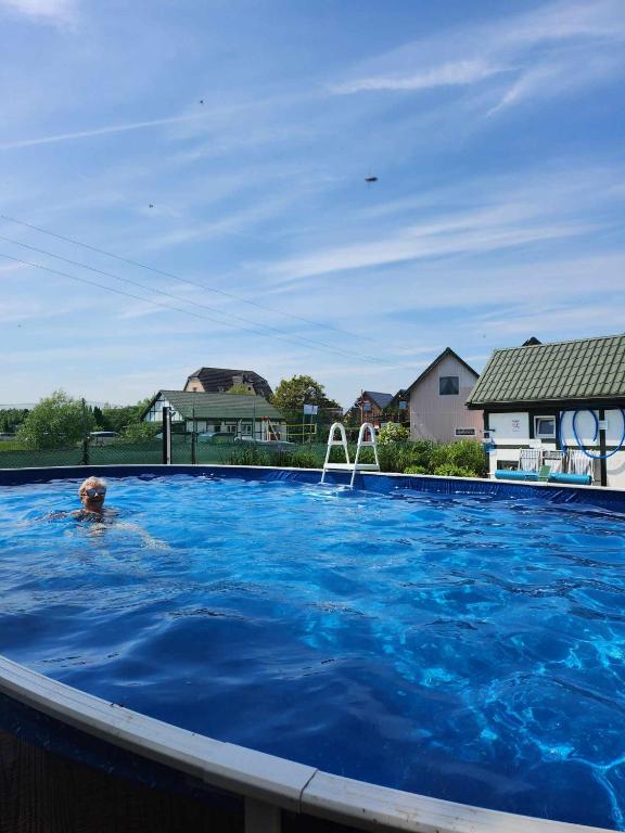 a person swimming in a large blue swimming pool at Ośrodek domków letniskowych Sztorm in Chłopy