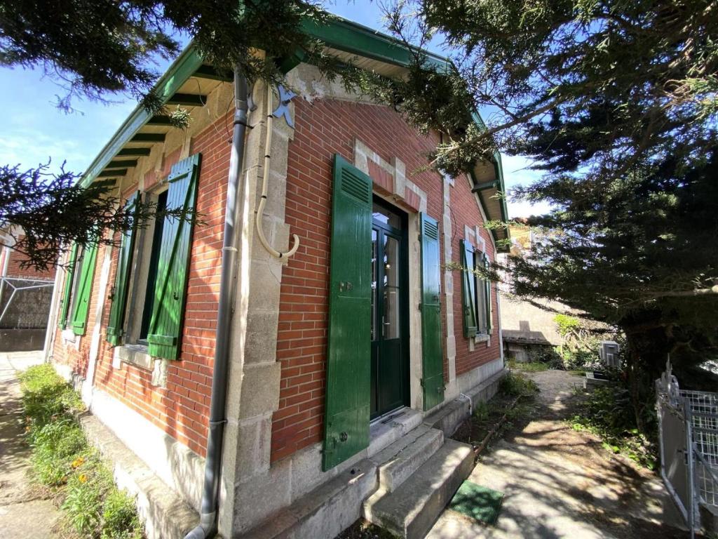 un bâtiment en briques rouges avec des portes vertes dans une rue dans l'établissement Résidence 103-soulac Sur Mer - 103 - Charmante Soulacaise proche des plages MAE-8881, à Soulac-sur-Mer