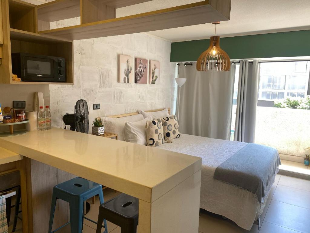 Un dormitorio con una cama y una cocina con encimera. en Lindo departamento tipo Loft en Ñuñoa, en Santiago
