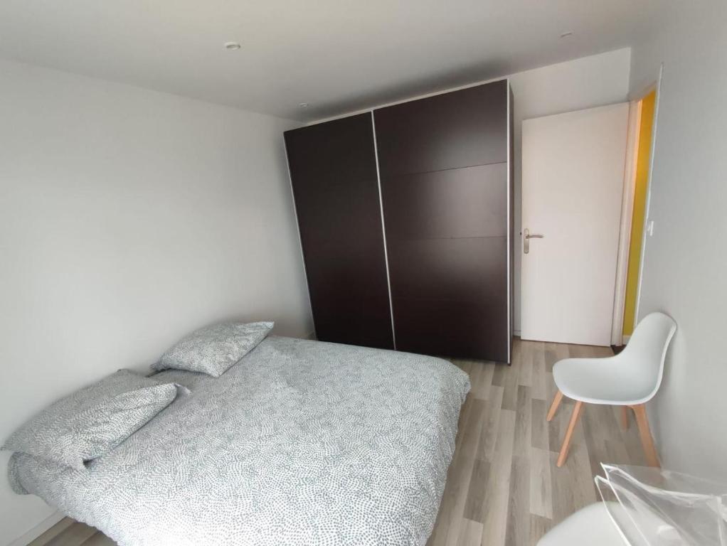 une chambre avec un lit et une chaise dedans dans l'établissement Appartement 3 chambres, à Brest