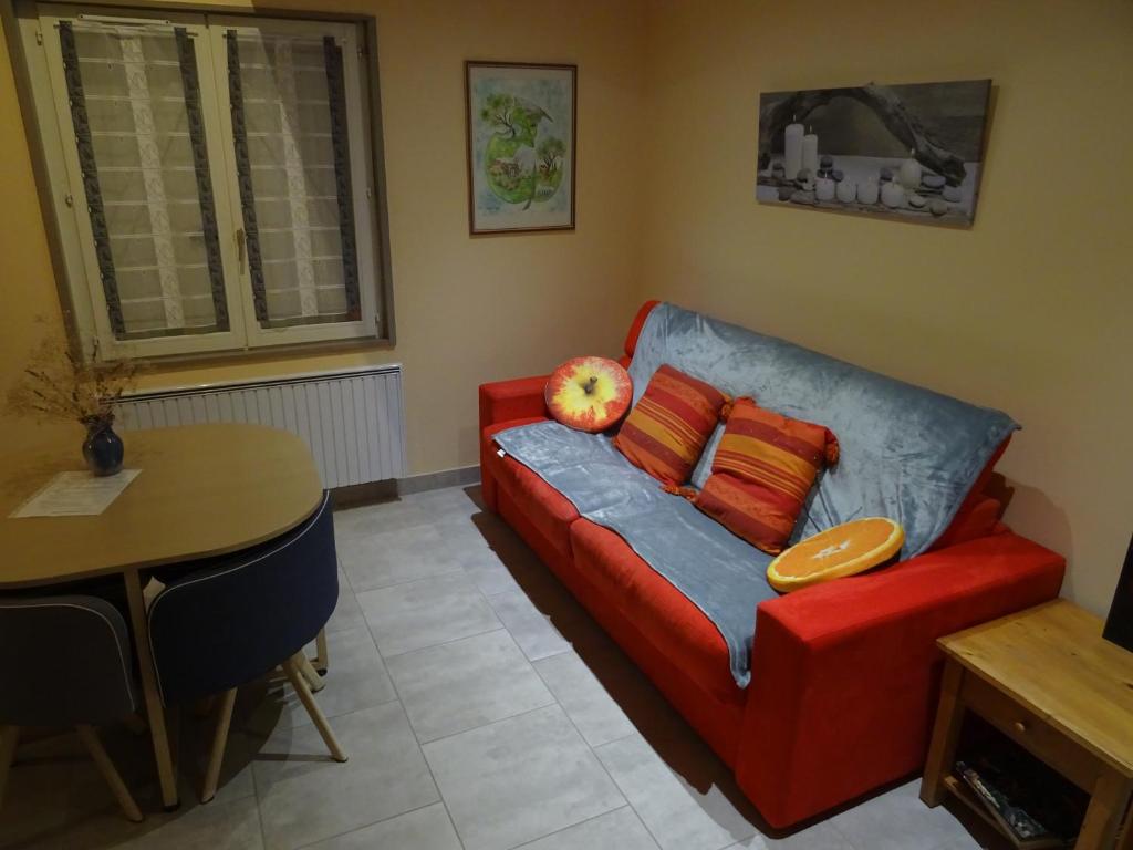 un salon avec un canapé rouge et une table dans l'établissement La Liberté dans le Beaujolais, à Lancié