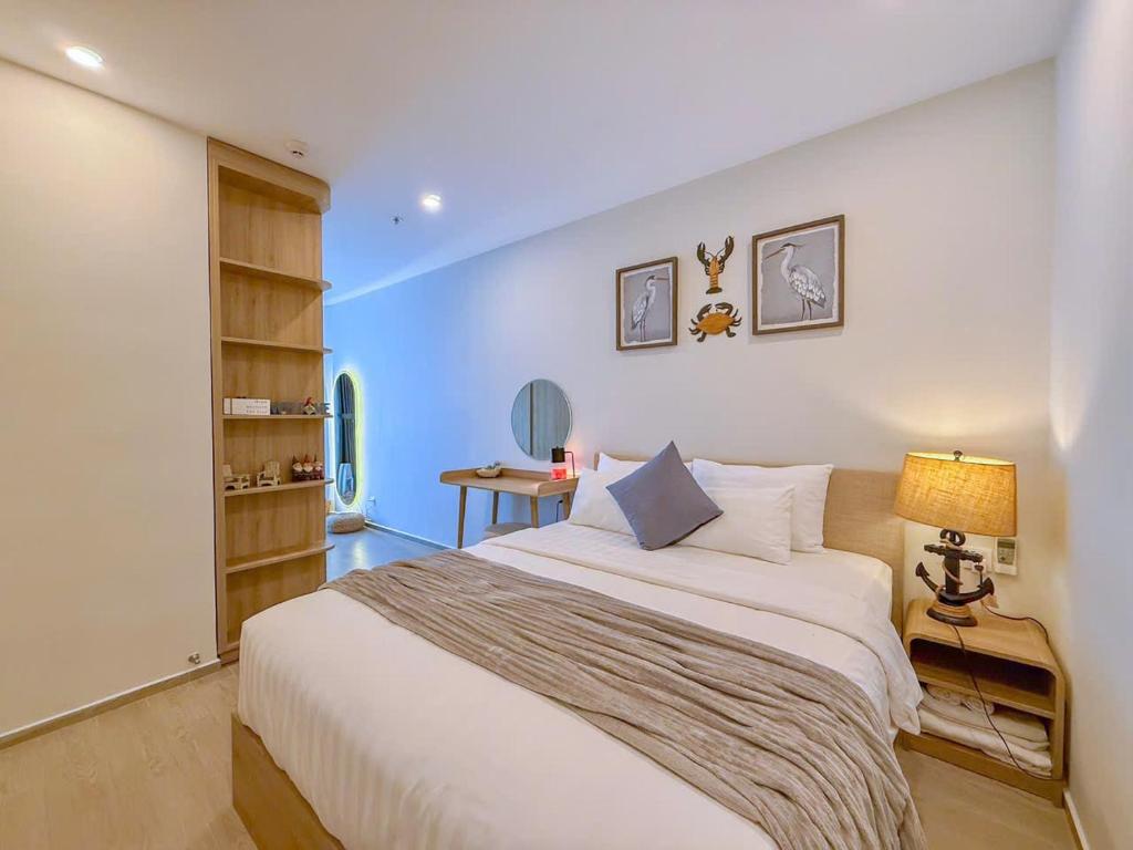a bedroom with a large white bed and a lamp at A cozy condotel in Bai Sau(1 bed and 1 sofa bed) in Vung Tau