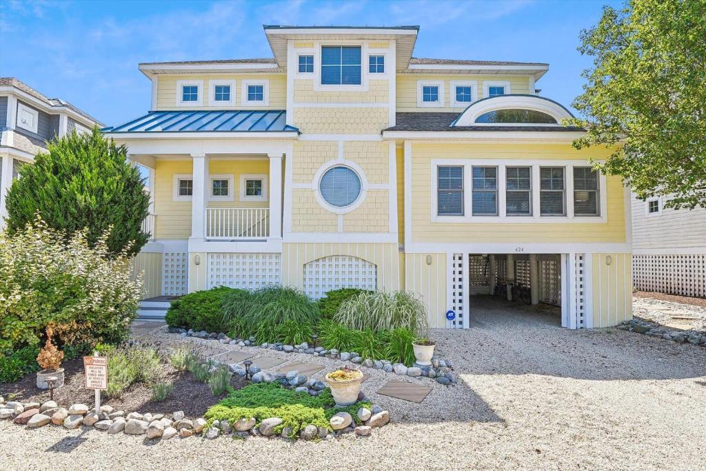 una casa amarilla con un paisaje delante de ella en Tingle avenue 624, en Bethany Beach
