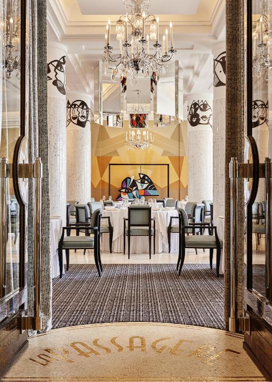 a dining room with a table and chairs and a chandelier at Hôtel Belles Rives in Juan-les-Pins