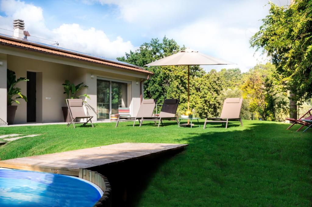 カステッリーナ・マリッティマにあるVilla La Leccina a Castellina Marittimaの庭園(椅子、パラソル、プール付)