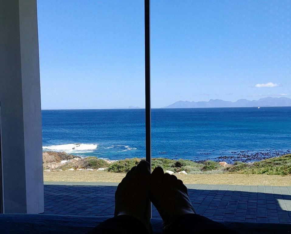 una persona tendida frente a una ventana con vistas al océano en ROMANZA APARTMeNT, en De Kelders