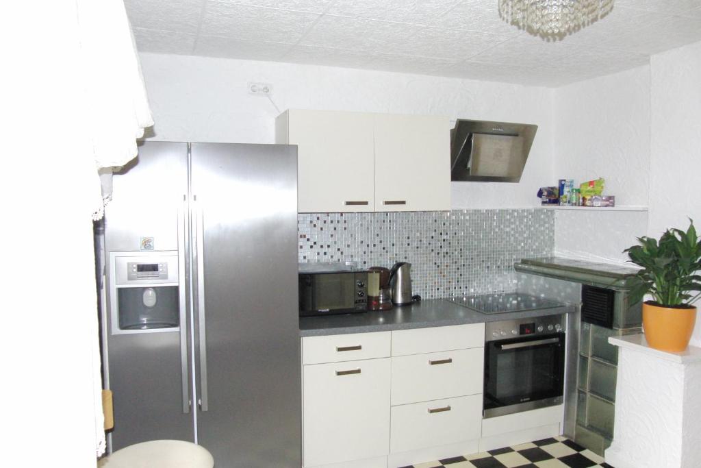 una cucina con frigorifero in acciaio inossidabile e armadietti bianchi di Ferienwohnung Volskyy a Treviri