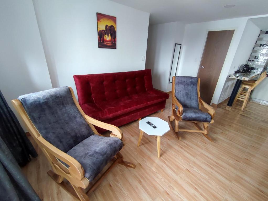 a living room with a red couch and two chairs at Apartahotel JDK in Armenia