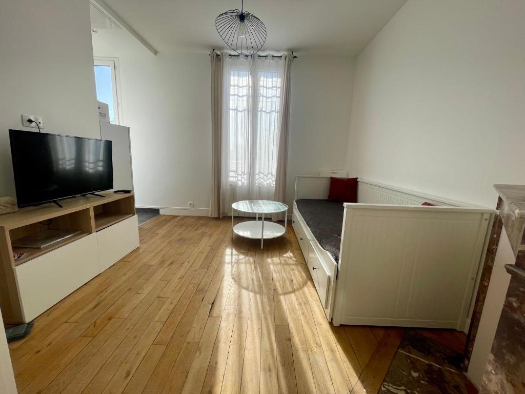 un salon avec un canapé et une télévision dans l'établissement F1 lumineux au cœur d'Argenteuil, à Argenteuil