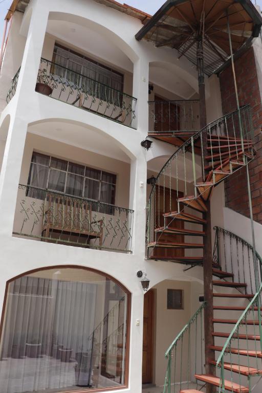 a three story building with stairs and balconies at Posada Kusillos in Puno