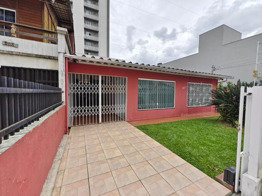 a red house with a gate in a yard at Central House in Itajaí