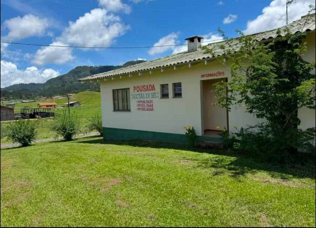 a small white building with a grass yard at Pousada Cristal de Gelo in Urubici