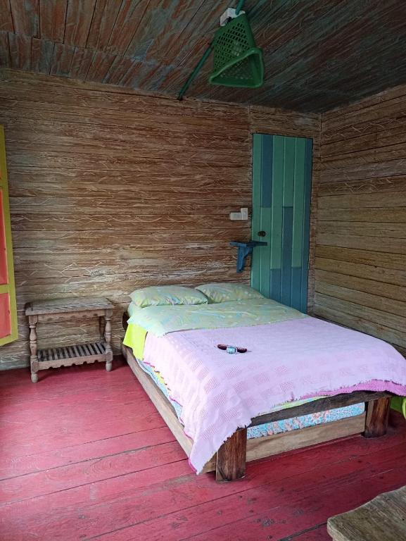 a bedroom with a bed in a wooden room at Hotel y Estadero Los Colores in Pajarito
