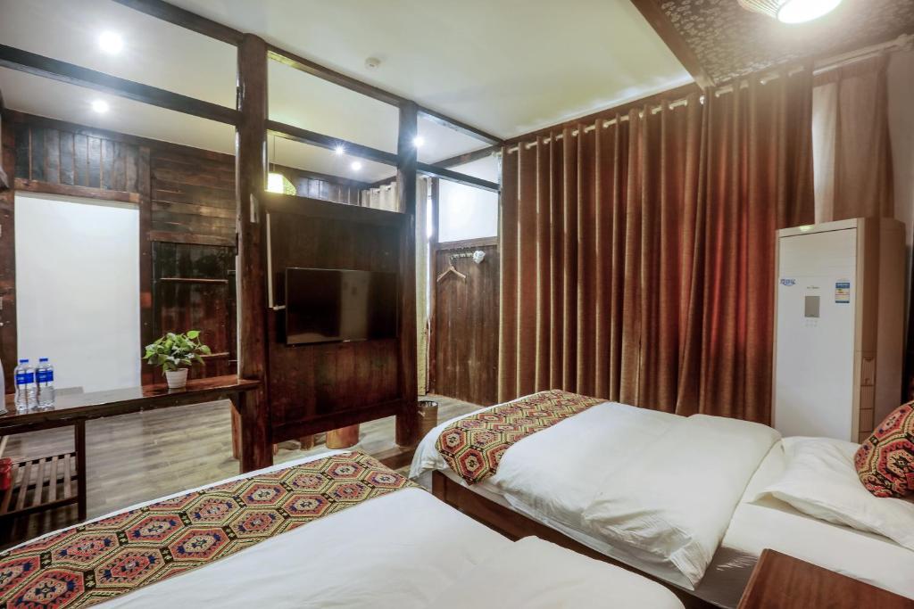 a hotel room with two beds and a television at 张家界畔山驿栈 in Zhangjiajie