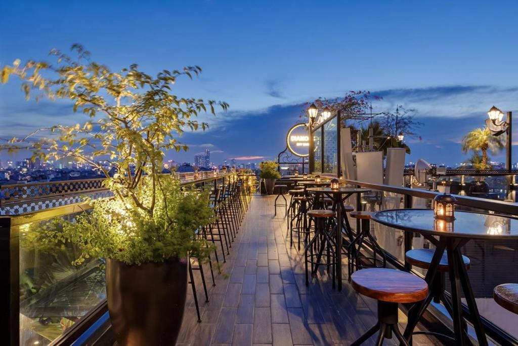 ハノイにあるLa Mejor Hotel & Sky Barのテーブルと椅子付きのレストランのバルコニー