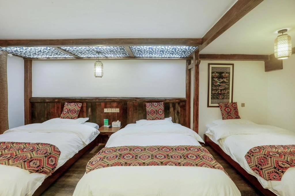 a room with three beds in it at 张家界畔山驿栈 in Zhangjiajie