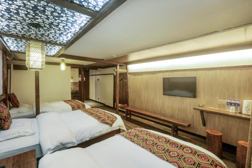 a hotel room with three beds and a television at 张家界畔山驿栈 in Zhangjiajie