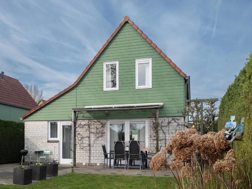 a green house with a table and chairs in a yard at Holiday Home in Quiet Dutch Park for Families in Wemeldinge