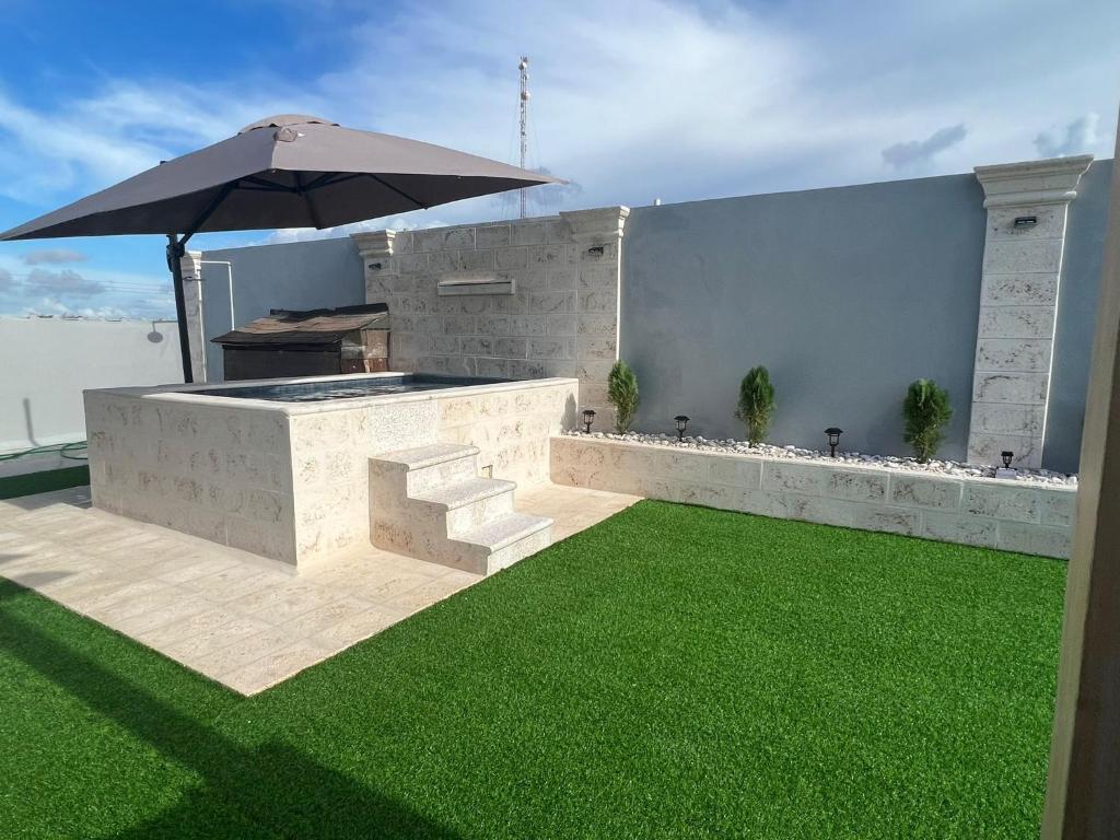 an outdoor bar with an umbrella and green grass at Hermoso Apartamento con Jacuzzi Privado in Punta Cana