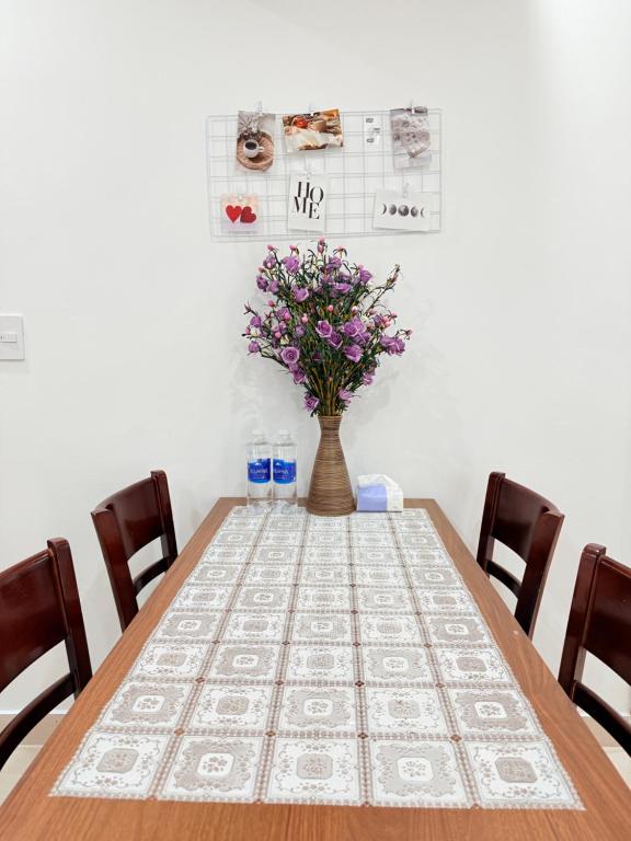 a table with a vase of flowers on top of it at Nhà Bơ Apartment at Nera Garden Huế in Thôn Văn Dương