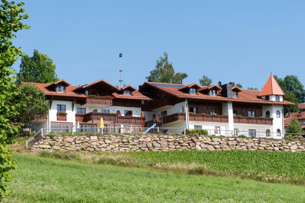 a large white house with a stone wall at Wellness Ferienwohnungen Zellertalblick in Drachselsried