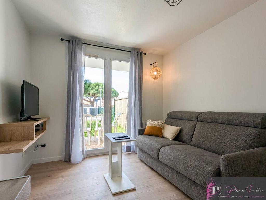 un salon avec un canapé et une télévision dans l'établissement Studio rénové avec jardin et accès piscine - FR-1-825-19, à La Rochelle