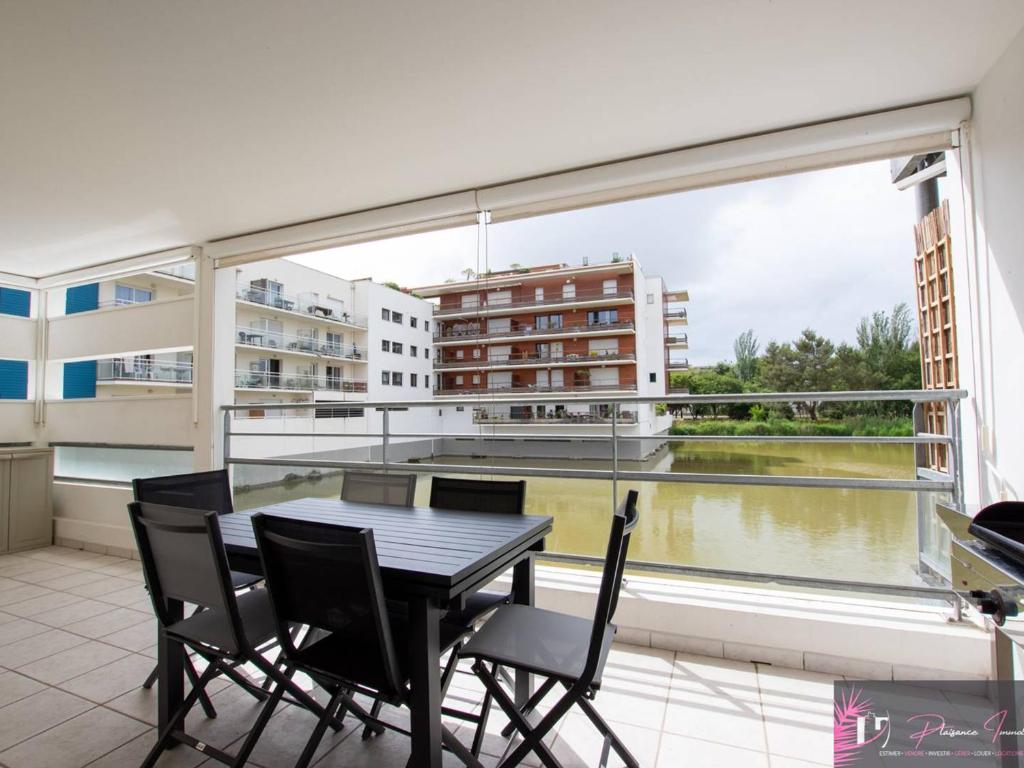 un balcon avec une table et des chaises et une grande fenêtre dans l'établissement Agréable T3 avec terrasse et parking à La Rochelle - FR-1-825-12, à La Rochelle