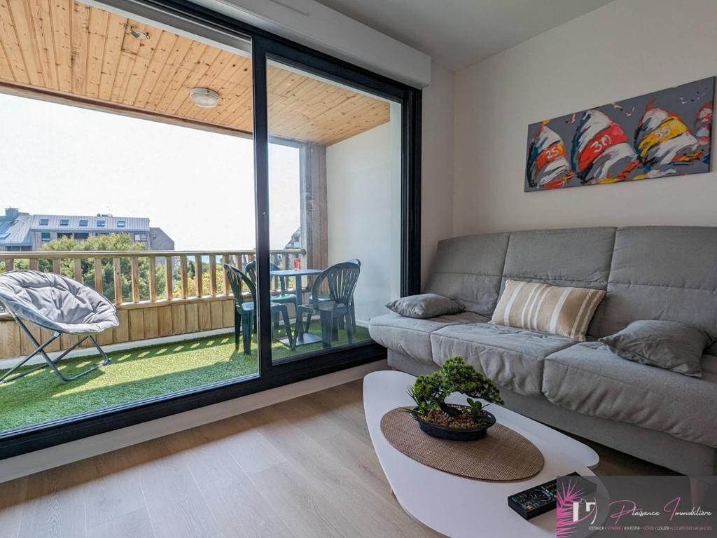 un salon avec un canapé et une grande fenêtre dans l'établissement Appartement rénové au pied de la plage avec balcon et parking - FR-1-825-46, à La Rochelle