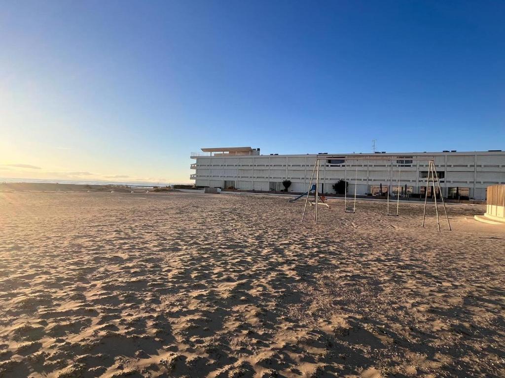 un bâtiment sur la plage avec un bâtiment en arrière-plan dans l'établissement Appartement lumineux sur plage avec piscine et parking - FR-1-716-81, au Grau-du-Roi