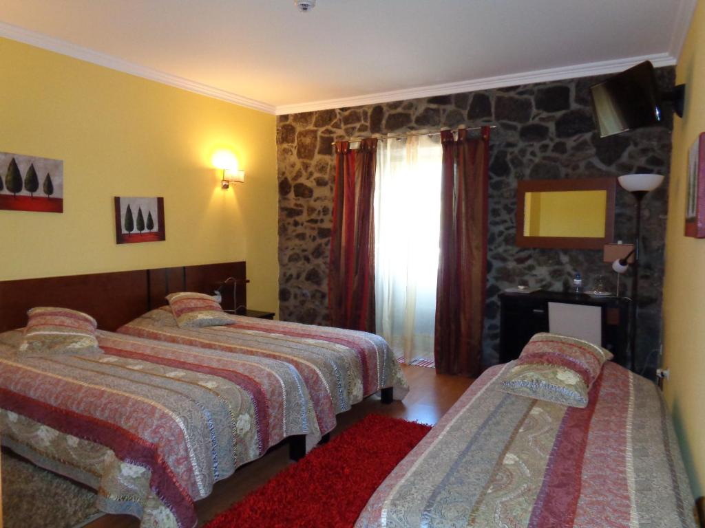 a bedroom with two beds and a stone wall at Casa Das Faias in Santa Cruz da Graciosa
