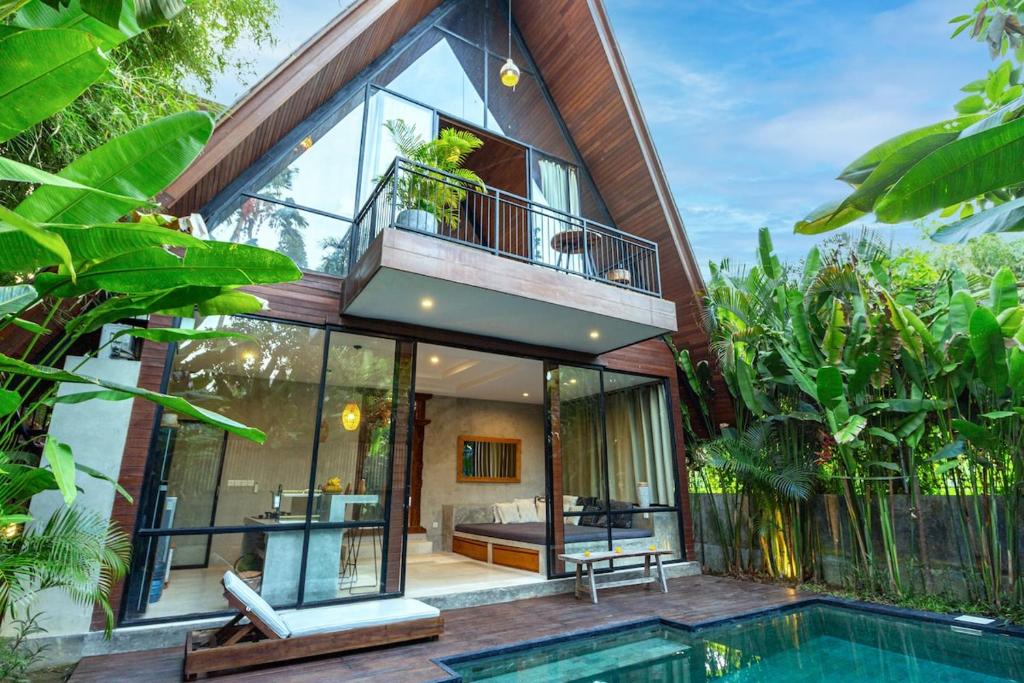 a house with a swimming pool in front of it at A Rustic Tropical Getaway with an Industrial Flair in Canggu
