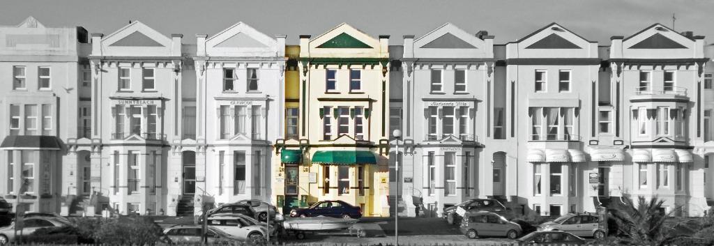 un gran edificio blanco con coches estacionados frente a él en Wulfruna Hotel, en Paignton