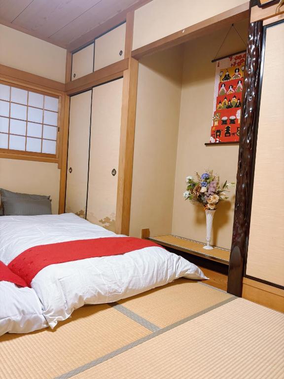 a bedroom with a bed and a vase of flowers at 桜の宿-大阪城Osaka castle-105m2 private-5Way access-KIX USJ 難波心斎橋 Direct in Osaka