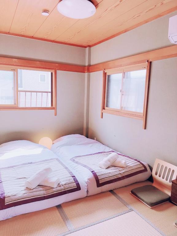 two beds in a room with two windows at 桜の宿-大阪城Osaka castle-105m2 private-5Way access-KIX USJ 難波心斎橋 Direct in Osaka