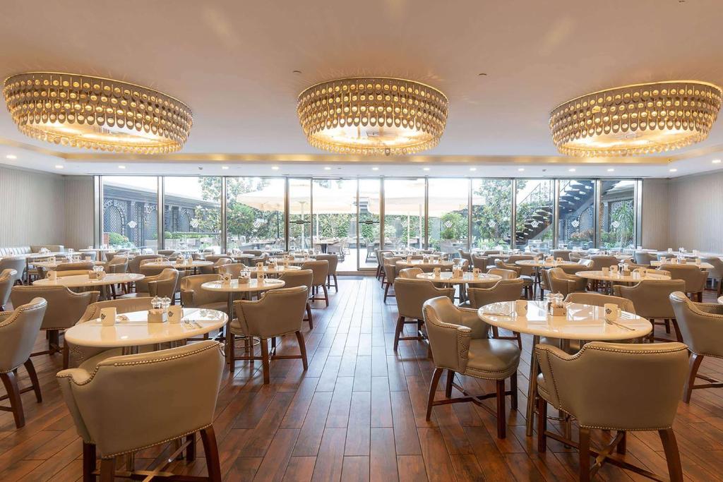 a restaurant with tables and chairs and large windows at Wyndham Grand Istanbul Kalamış Marina Hotel in Istanbul