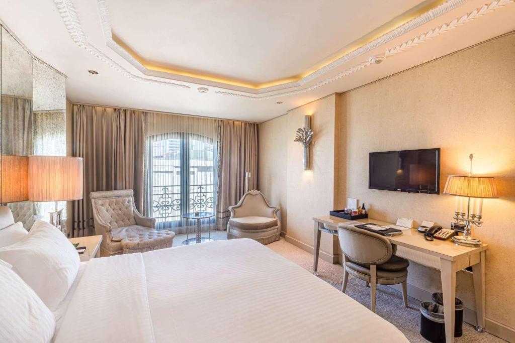 a hotel room with a bed and a desk and a television at Wyndham Grand Istanbul Kalamış Marina Hotel in Istanbul