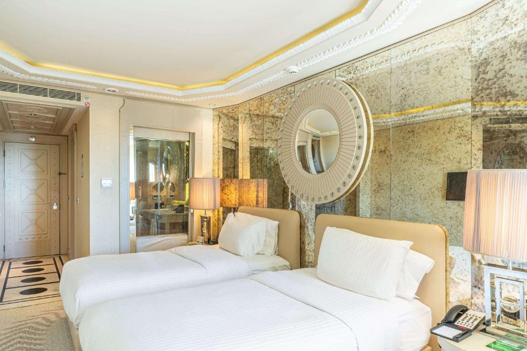 a bedroom with two beds and a mirror at Wyndham Grand Istanbul Kalamış Marina Hotel in Istanbul