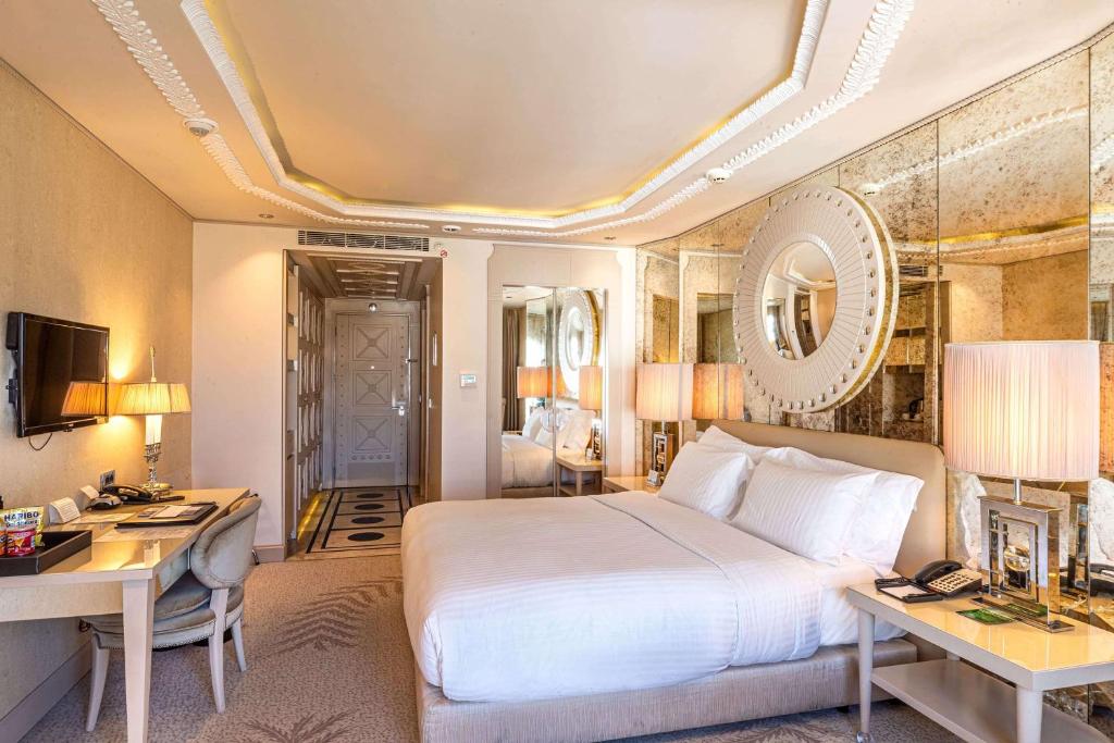 a hotel room with a bed and a desk and a desk at Wyndham Grand Istanbul Kalamış Marina Hotel in Istanbul