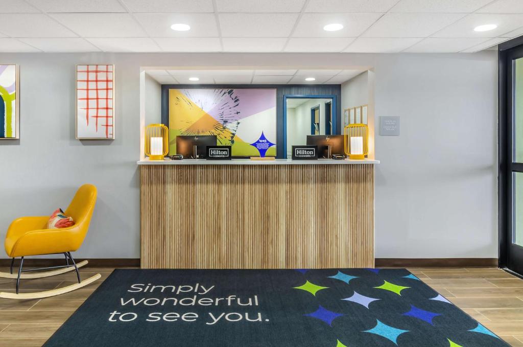 a lobby with a reception desk and a yellow chair at Spark By Hilton Roanoke Airport in Roanoke