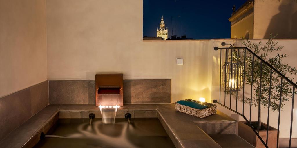 un edificio con bañera de hidromasaje en un balcón por la noche en Hotel Boutique Corral del Rey, en Sevilla