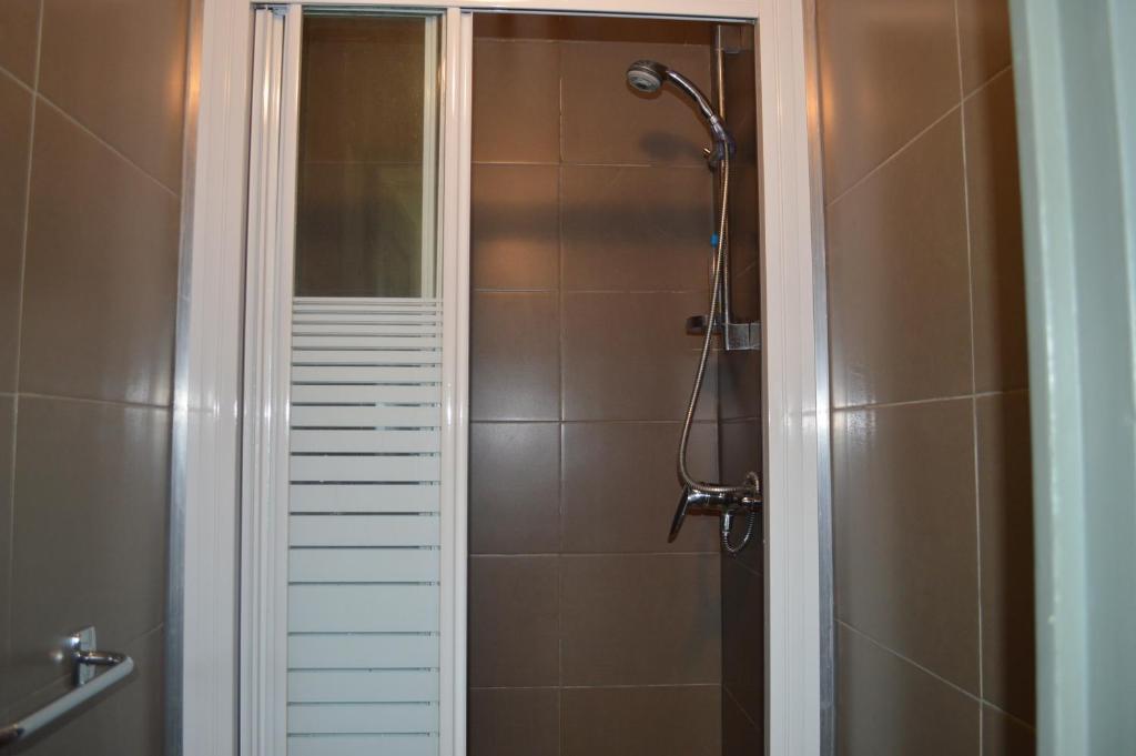 a shower in a bathroom with brown tiles at Backpackers Chez Patrick in Nice