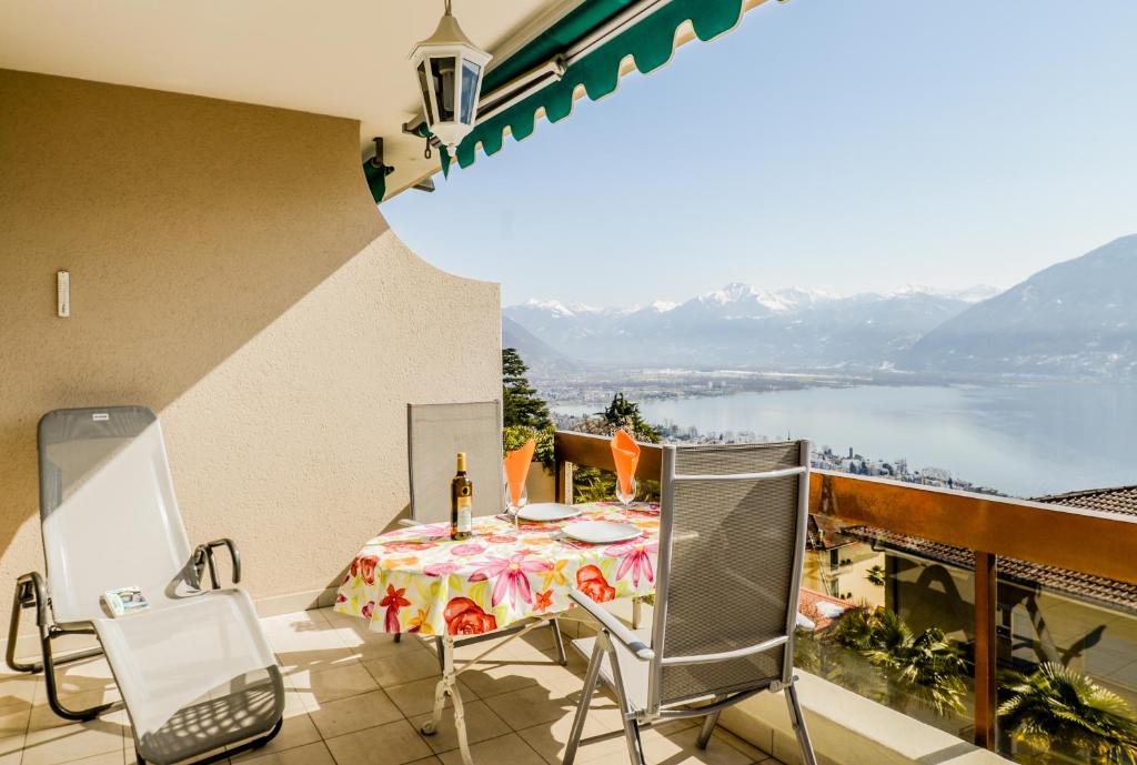 einen Balkon mit einem Tisch und Stühlen sowie Blick auf das Wasser in der Unterkunft Collina d'Oro Orselina Locarno in Locarno