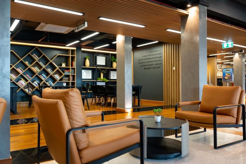 The lobby has leather lounge chairs, a round coffee table, bookshelves, and a piano.