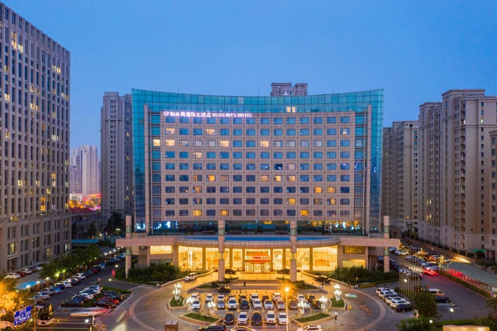 a large building with cars parked in a parking lot at Bliss International Hotel in Weihai