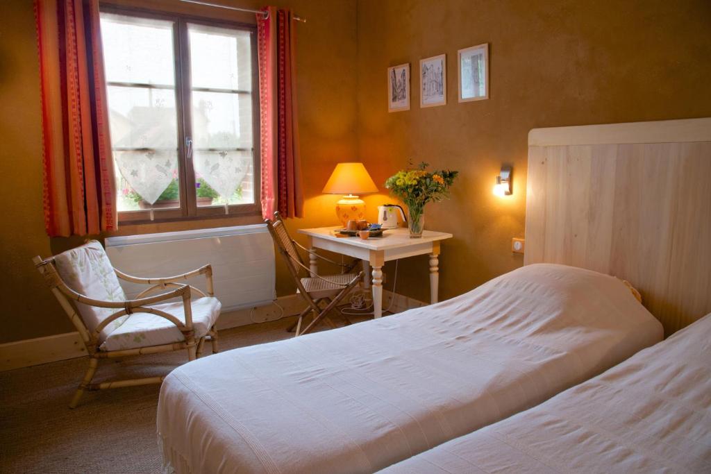 a bedroom with a bed and a chair and a table at Le Petit Saint-Julien in Saint-Julien-les-Villas