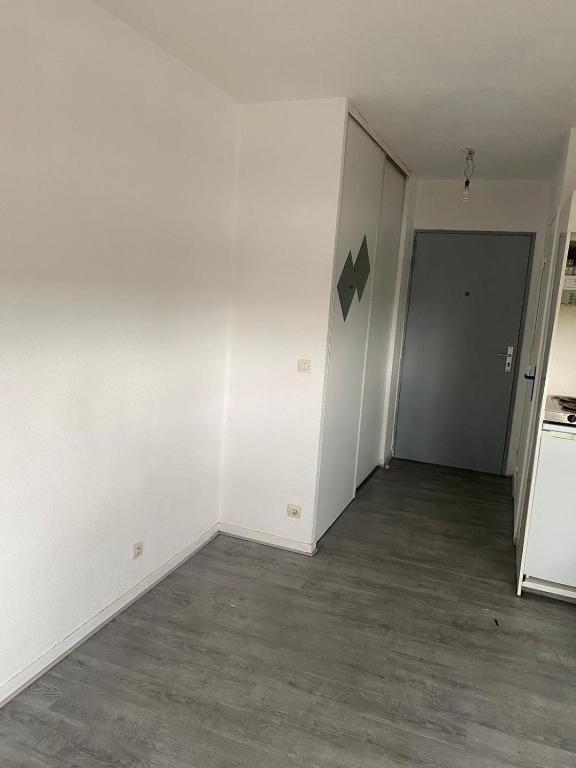 une pièce vide avec des murs blancs et une porte dans l'établissement Appartement Cosy Elancourt, à Élancourt