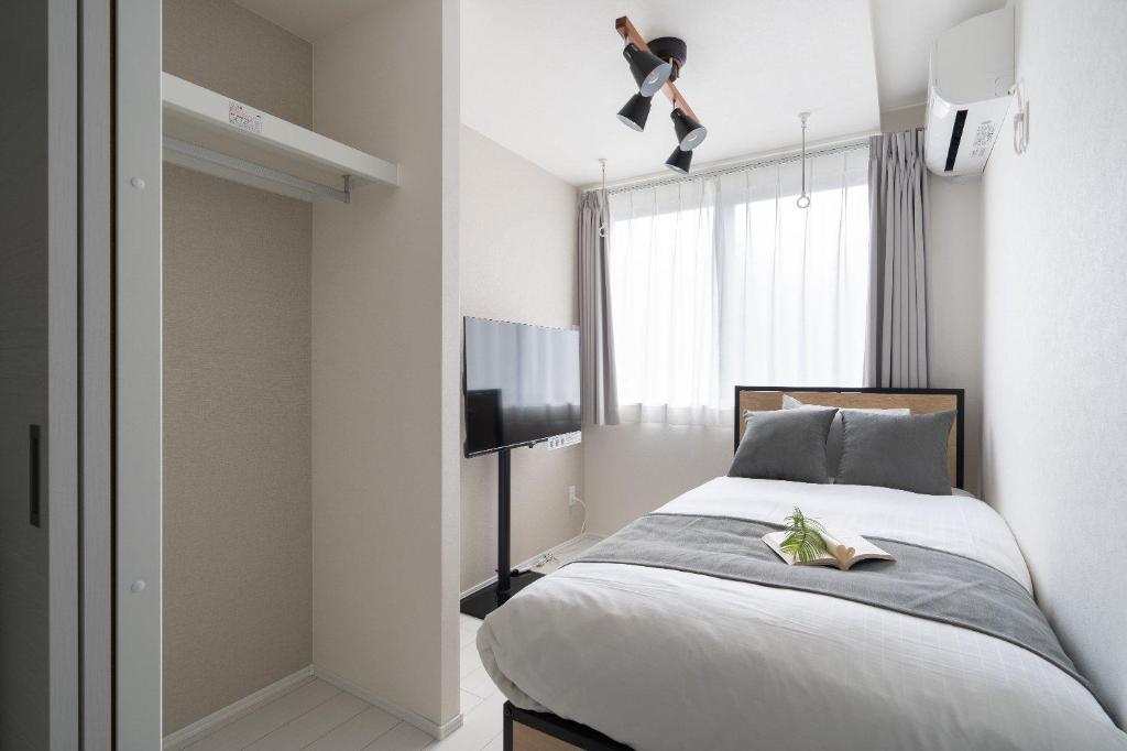 a bedroom with a bed and a flat screen tv at Brio Takaido in Tokyo